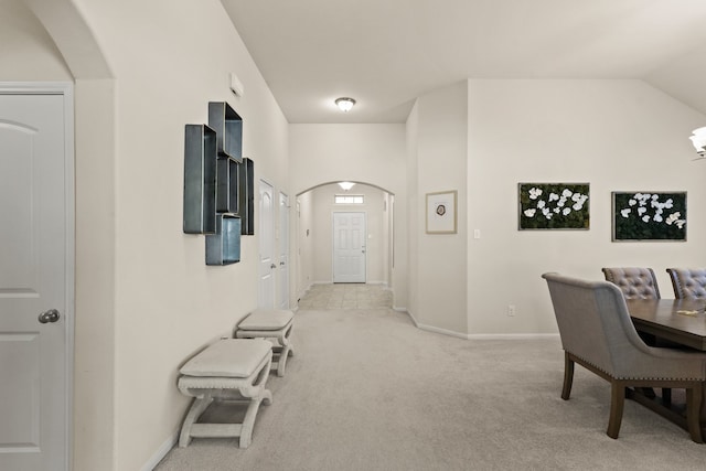 hallway with light colored carpet and lofted ceiling