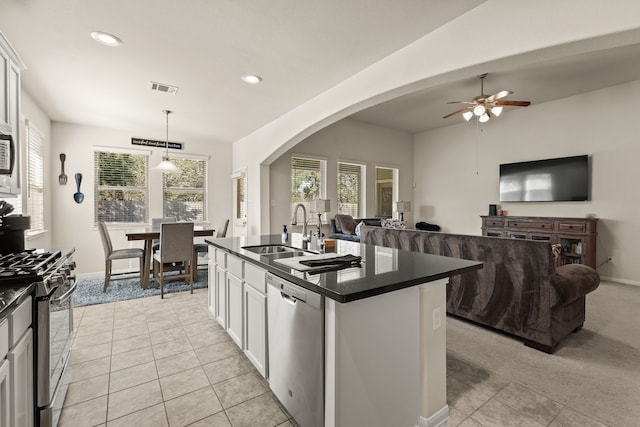 kitchen with stainless steel appliances, sink, pendant lighting, white cabinets, and an island with sink