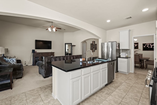 kitchen featuring light colored carpet, ceiling fan, sink, a center island with sink, and white cabinetry