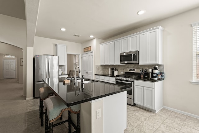 kitchen featuring sink, a kitchen bar, a center island with sink, white cabinets, and appliances with stainless steel finishes