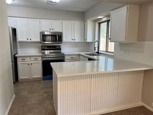 kitchen with white cabinetry, kitchen peninsula, appliances with stainless steel finishes, and tasteful backsplash