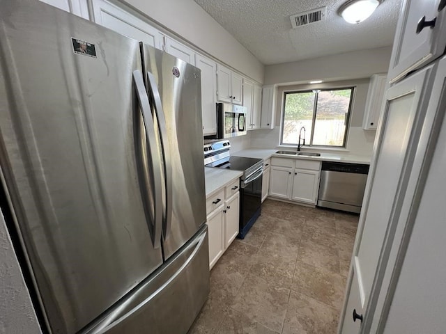 kitchen with sink, white cabinets, a textured ceiling, and appliances with stainless steel finishes