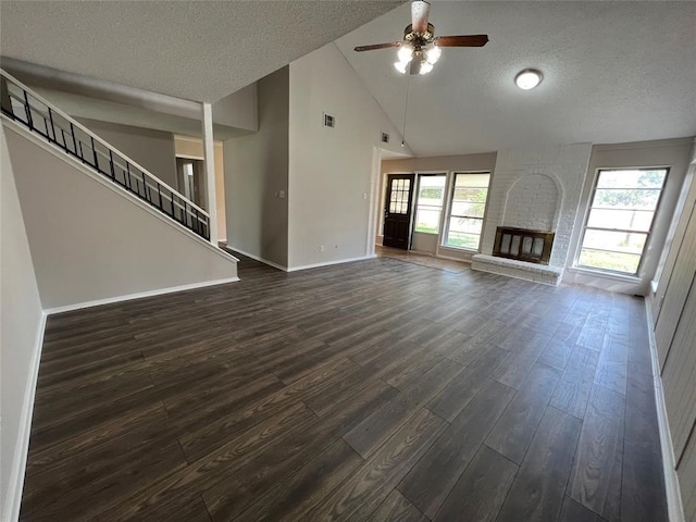 unfurnished living room with ceiling fan, a brick fireplace, high vaulted ceiling, dark hardwood / wood-style floors, and a textured ceiling