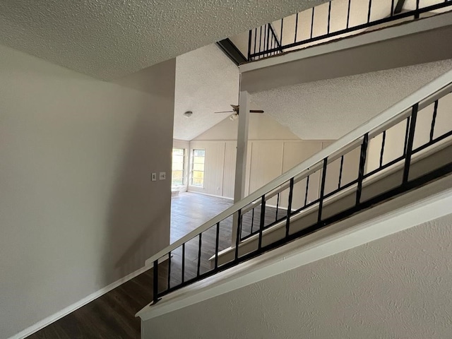 stairs with a textured ceiling, hardwood / wood-style flooring, vaulted ceiling, and ceiling fan