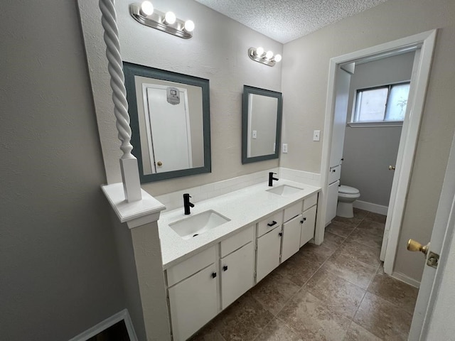 bathroom with vanity, toilet, and a textured ceiling