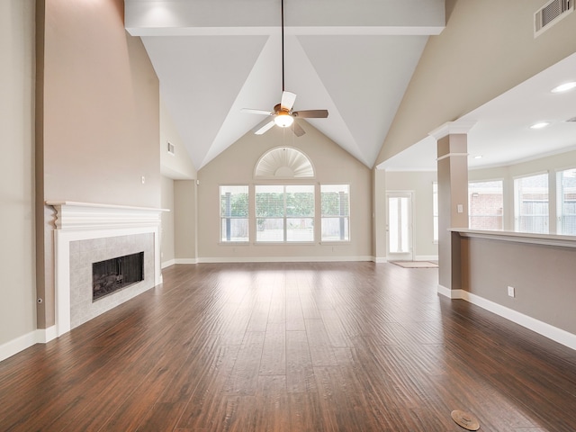 unfurnished living room with a tile fireplace, dark hardwood / wood-style flooring, high vaulted ceiling, and beamed ceiling