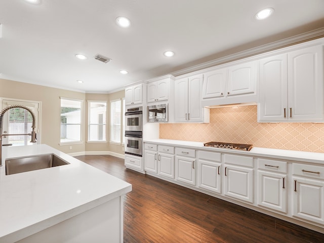 kitchen with decorative backsplash, appliances with stainless steel finishes, sink, white cabinets, and dark hardwood / wood-style floors