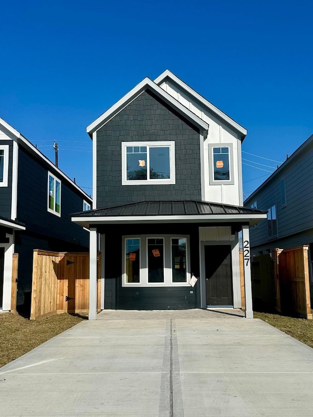 view of front of house with metal roof, fence, and a standing seam roof