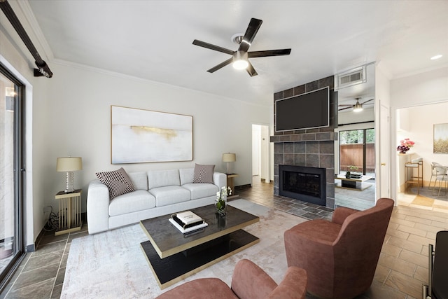 living room featuring a tile fireplace, ceiling fan, and crown molding