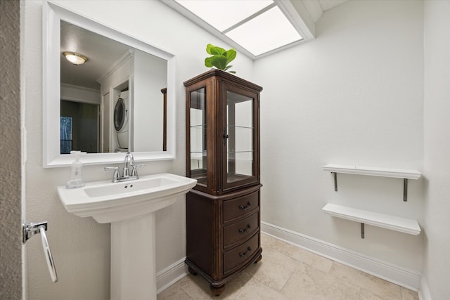 bathroom with tile patterned flooring, stacked washer and clothes dryer, and ornamental molding