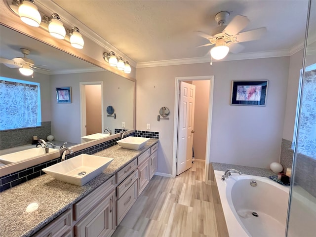 bathroom with a washtub, hardwood / wood-style floors, vanity, and ornamental molding