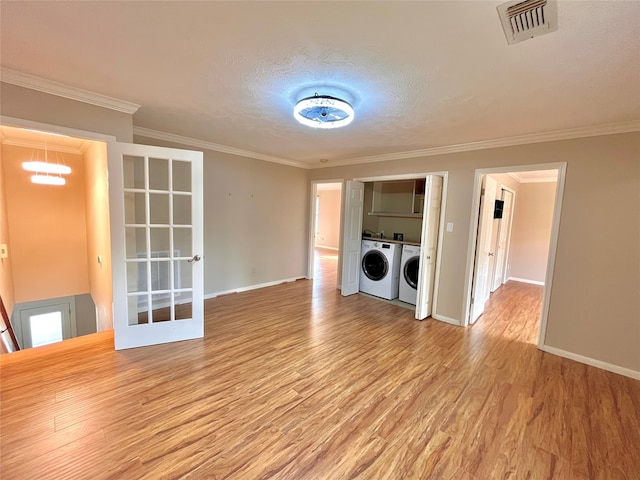 clothes washing area with a textured ceiling, light hardwood / wood-style floors, ornamental molding, and washing machine and clothes dryer