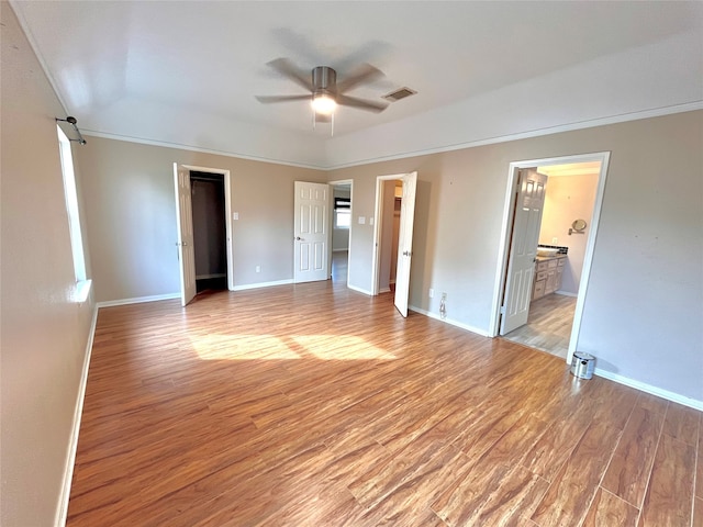 unfurnished bedroom with ceiling fan, light hardwood / wood-style floors, a spacious closet, and connected bathroom