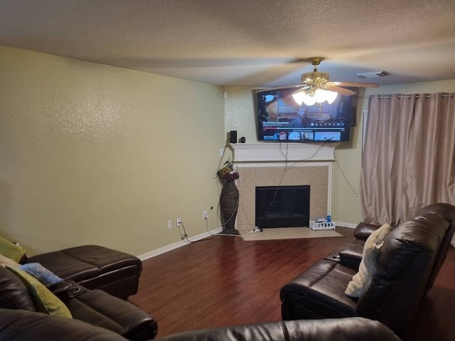 living room with ceiling fan, a fireplace, a textured ceiling, and hardwood / wood-style flooring