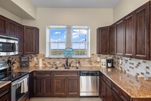 kitchen with light stone countertops, sink, stainless steel appliances, backsplash, and light tile patterned flooring