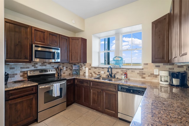 kitchen with light stone countertops, appliances with stainless steel finishes, tasteful backsplash, sink, and light tile patterned floors