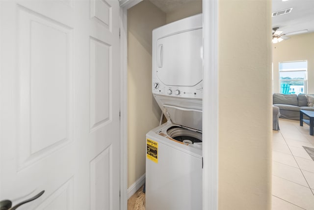 laundry room featuring light tile patterned floors, stacked washer and dryer, and ceiling fan