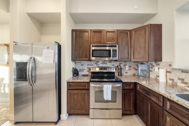 kitchen featuring light stone counters, light tile patterned floors, appliances with stainless steel finishes, and tasteful backsplash