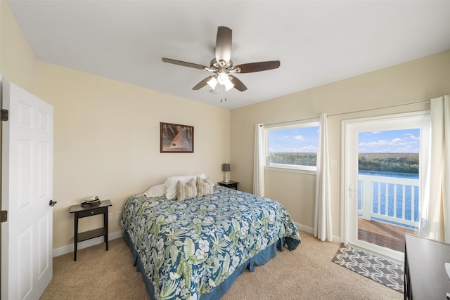 carpeted bedroom featuring ceiling fan and a water view