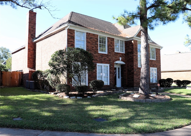 colonial-style house featuring a front yard and central AC