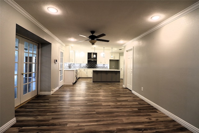 kitchen with a center island, dark wood-type flooring, wall chimney range hood, crown molding, and white cabinets