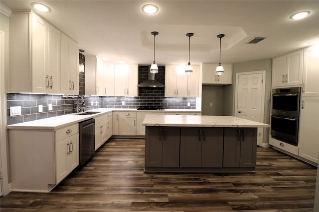 kitchen featuring wall chimney exhaust hood, a center island, white cabinetry, and decorative light fixtures