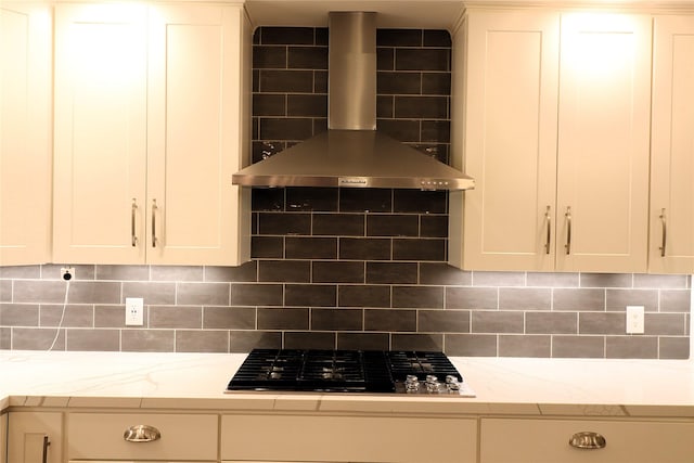 2304 Eagles Way, Pearland, TX 77581 - kitchen with wall chimney exhaust hood, stovetop, decorative backsplash, white cabinets, and light stone counters