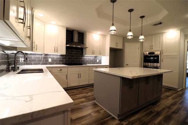 kitchen with dark hardwood / wood-style flooring, a center island, wall chimney range hood, and sink