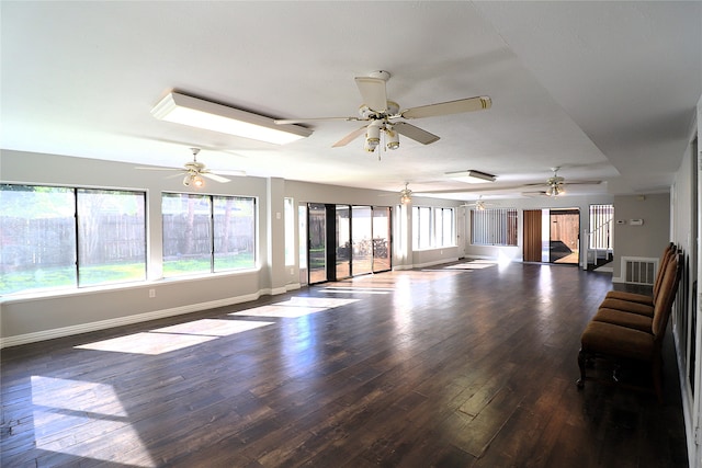 unfurnished living room with ceiling fan and dark wood-type flooring