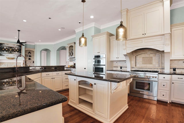 kitchen featuring appliances with stainless steel finishes, dark hardwood / wood-style flooring, decorative light fixtures, dark stone countertops, and a kitchen island