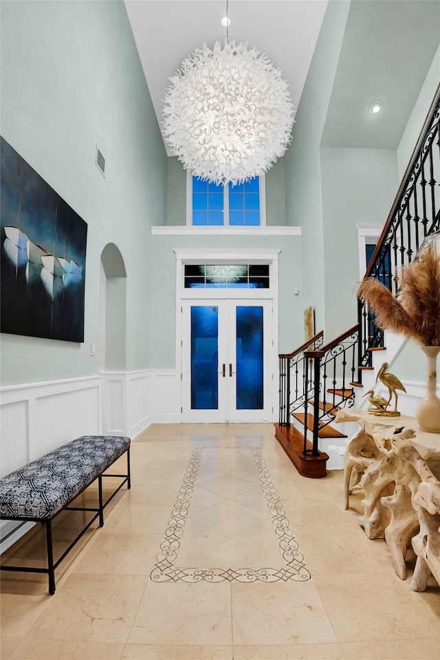 foyer featuring french doors, a high ceiling, and an inviting chandelier