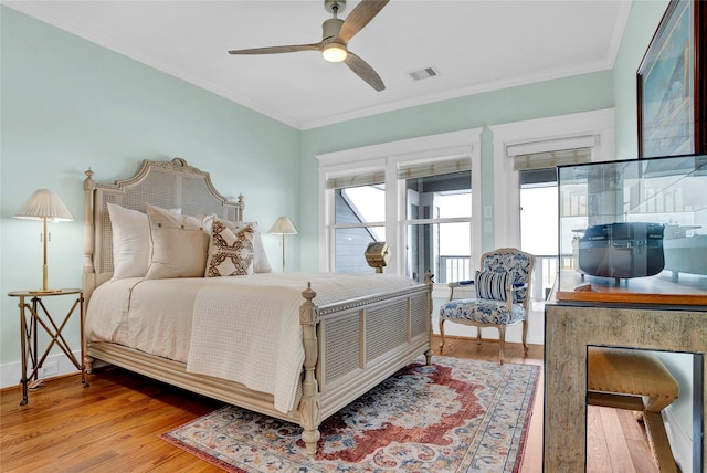 bedroom with hardwood / wood-style floors, multiple windows, ornamental molding, and ceiling fan