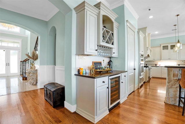 bar featuring ornamental molding, decorative light fixtures, white cabinetry, light hardwood / wood-style floors, and wine cooler