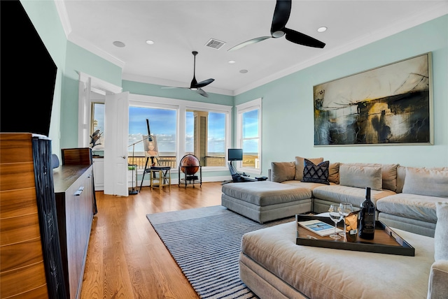 living room with light hardwood / wood-style floors, ceiling fan, and crown molding