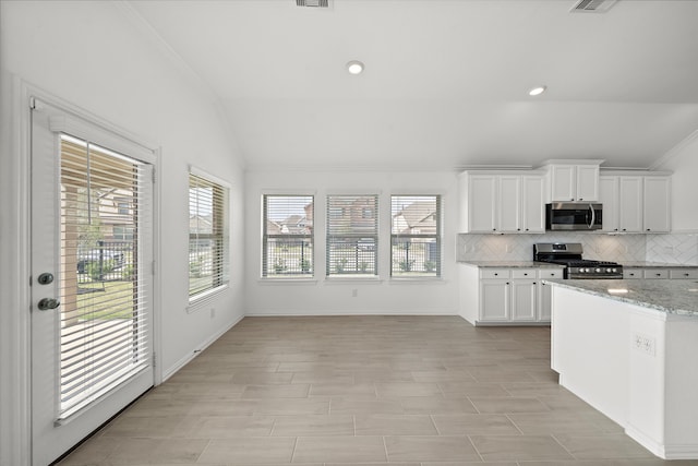 kitchen with stainless steel appliances, tasteful backsplash, light stone counters, lofted ceiling, and white cabinets