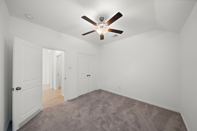 unfurnished bedroom with ceiling fan, a closet, light carpet, and vaulted ceiling