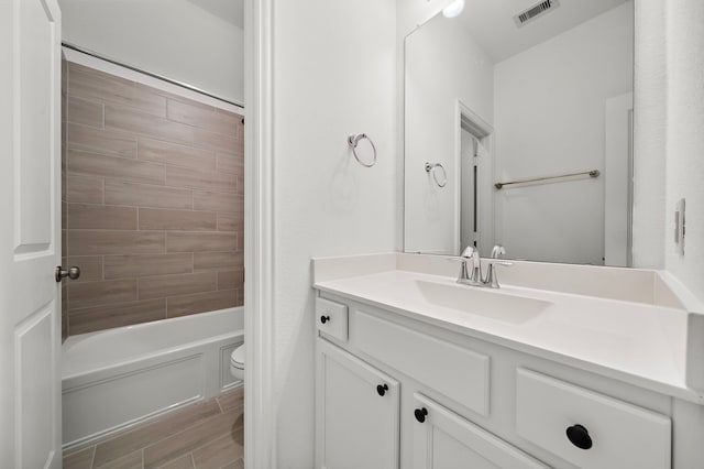 full bathroom with hardwood / wood-style flooring, vanity, toilet, and tiled shower / bath combo