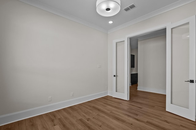 unfurnished bedroom with crown molding, a closet, wood-type flooring, and french doors