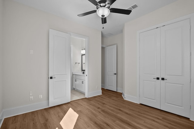 unfurnished bedroom with light wood-type flooring, a closet, ceiling fan, and ensuite bathroom