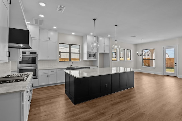 kitchen with white cabinetry, a chandelier, appliances with stainless steel finishes, a kitchen island, and pendant lighting