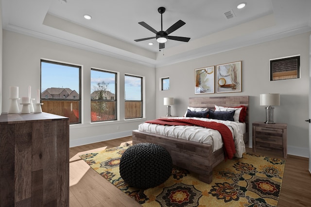 bedroom featuring hardwood / wood-style floors, ceiling fan, and a tray ceiling