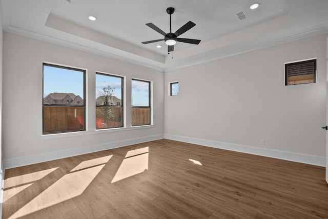 spare room featuring hardwood / wood-style flooring, crown molding, ceiling fan, and a tray ceiling