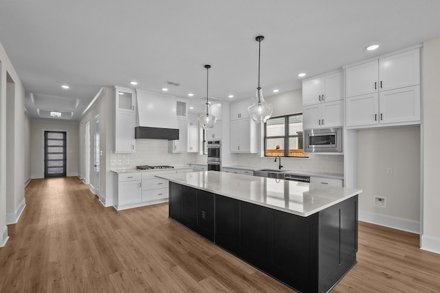 kitchen featuring premium range hood, white cabinetry, sink, a center island, and stainless steel appliances