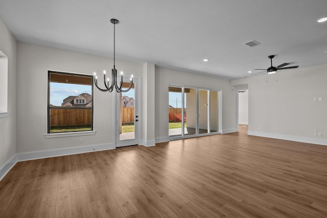 unfurnished dining area featuring ceiling fan with notable chandelier, plenty of natural light, and hardwood / wood-style flooring