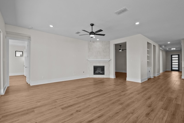 unfurnished living room with a tiled fireplace, ceiling fan, and light hardwood / wood-style flooring