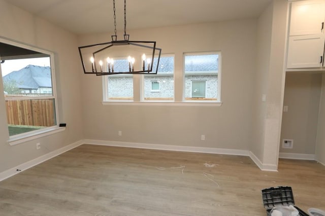 unfurnished dining area featuring a notable chandelier and light wood-type flooring