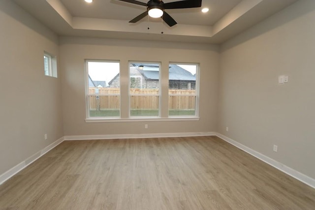 unfurnished room with ceiling fan, a healthy amount of sunlight, and a tray ceiling