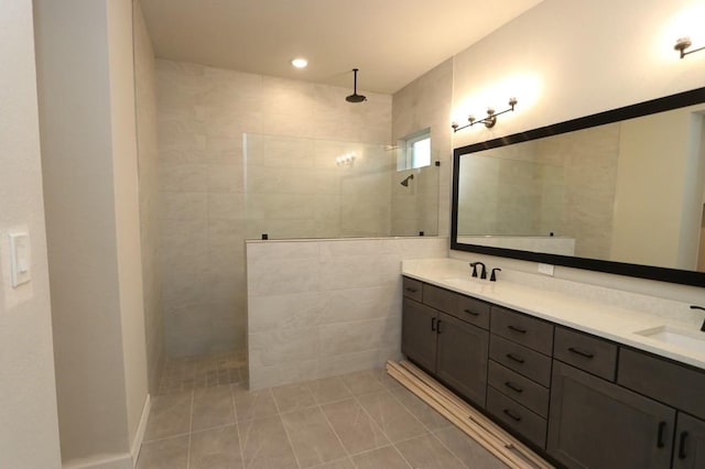 bathroom with tile patterned floors, vanity, and tiled shower