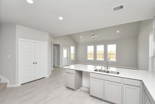 kitchen featuring ceiling fan, sink, light hardwood / wood-style flooring, gray cabinets, and lofted ceiling