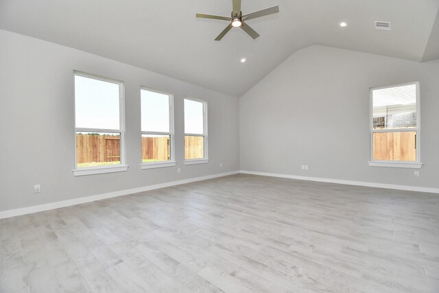 empty room with a wealth of natural light, light hardwood / wood-style floors, and lofted ceiling